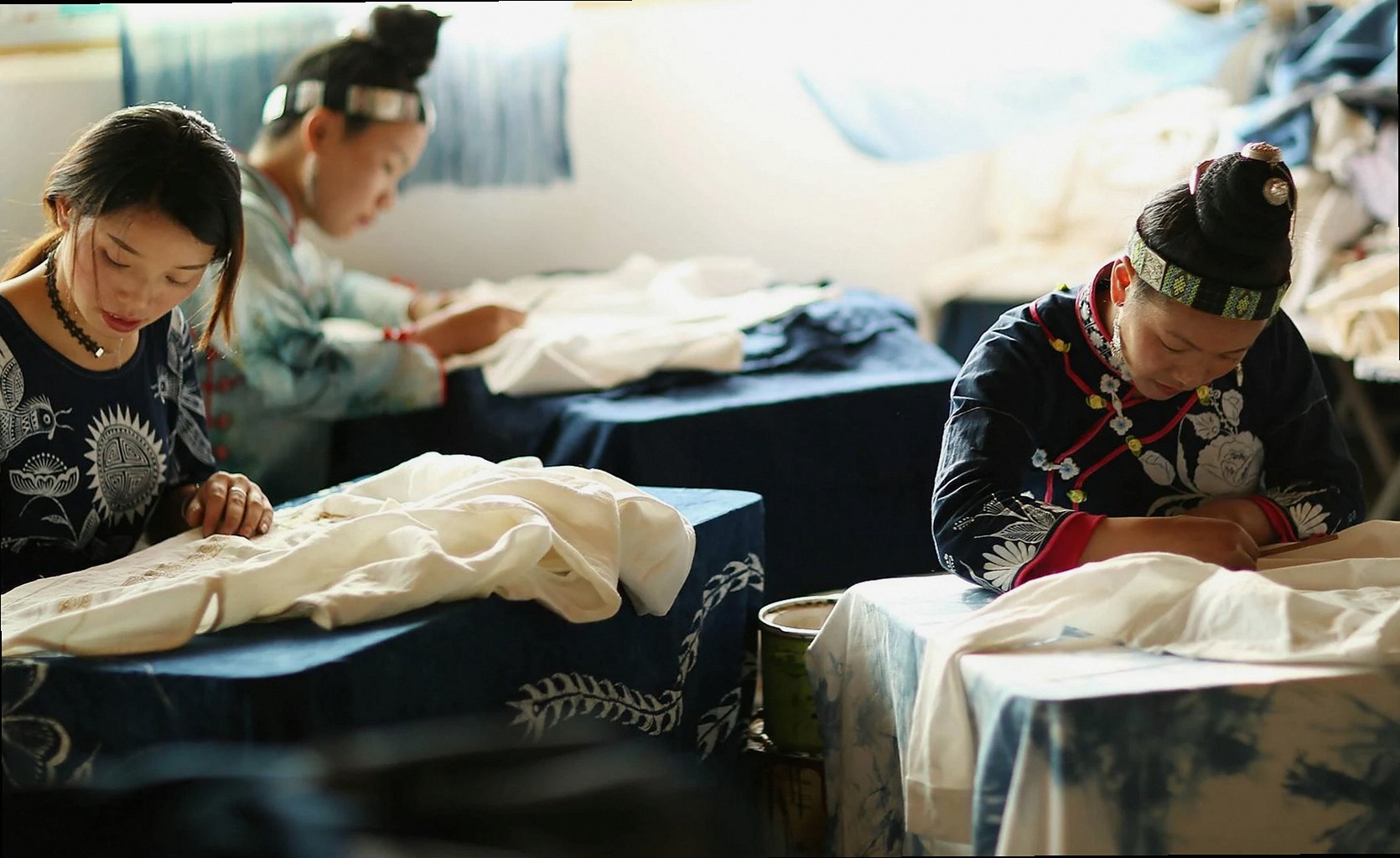 Femmes artisanes concentrées brodant du tissu, mettant en valeur des techniques artisanales traditionnelles en intérieur
